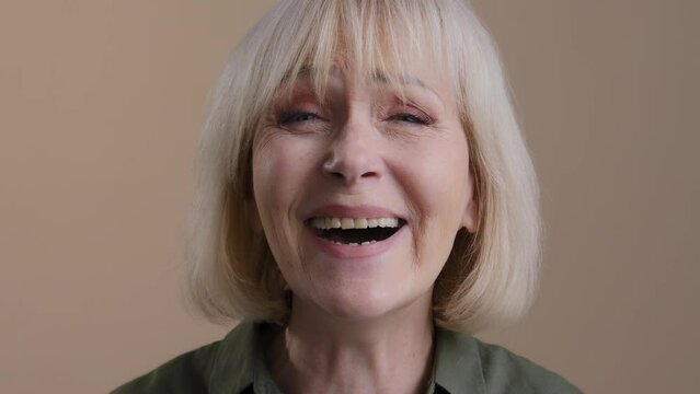 Portrait smiling caucasian mature grey-haired funny woman laughing indoors. Happy carefree middle aged lady laugh with joke fun good mood, senior female toothy smile close up face headshot in studio
