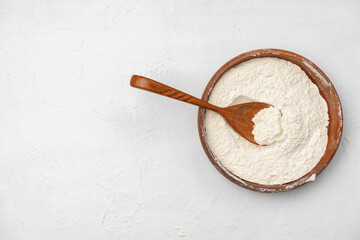Pile of flour in wooden spoon on white background