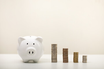 white piggy bank and coins on a white background, for saving money wealth, and financial concepts,...