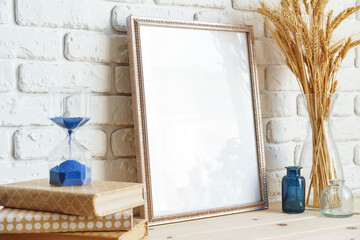 Vase with ears of wheat and photo frames against brick wall
