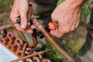 Worker plumber are cutting off copper pipe with pipe scissors.