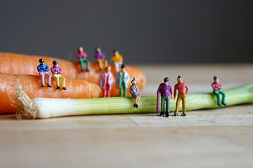 Miniature figurine character: people sitting on carrots and spring onions, and some standing on...