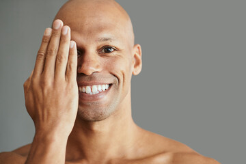 Obraz premium Studio portrait of happy black man covering half face with hand and looking at camera.