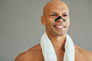 Happy black man purifying his skin with charcoal cleansing nose strips.