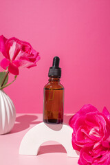 Glass dropper bottle on podium with rose flower. Hyaluronic acid oil, serum with collagen and...