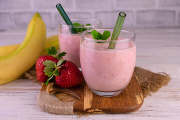 Two glasses with fresh strawberry and banana smoothie.
