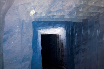 Ice cave inside rhone glacier, ice corridor with frozen blue walls.