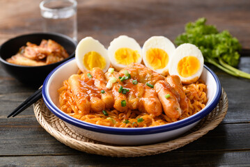 Korean spicy instant noodle with Tteokbokki, sausage and egg on wooden background