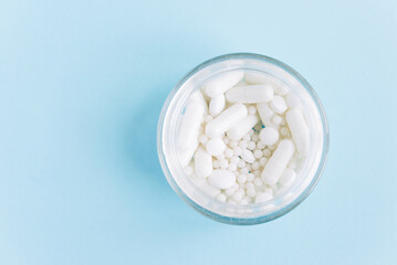 Different white pills and a  container on a blue background. Medical theme.	