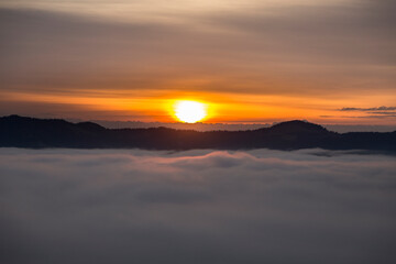 Fototapeta na wymiar Morning orange sunbeams over misty clouds in the mountains