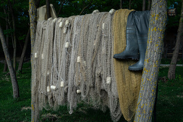 Fishing nets drying on a crossbar between trees and fishing boots