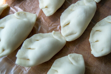 Fototapeta na wymiar raw dumplings lie in a row. dumplings with meat. finished semi-finished product. Horizontal image