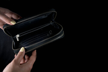 Empty black wallet in hands on a black background