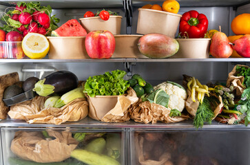 Opened refrigerator full of vegetarian healthy fresh fruit, vegetables, rich in antioxidant, vibrant food inside on fridge. Healthy nutrition. Detox. Diet. Zero waste grocery shopping concept. 