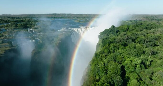 Spectacular high aerial fly over view looking through a rainbow at the scenic Victoria falls. Unesco world heritage site