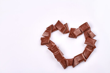 Close-up heart made of chocolate bar pieces top view. Isolated on white background.