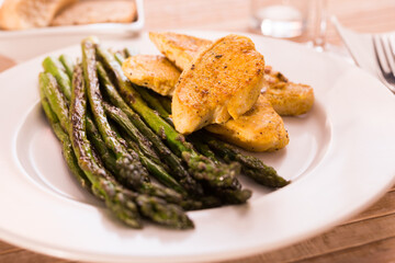 cooked dish. Chicken nuggets with green asparagus on plate