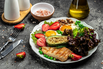 Plate with keto diet food. Keto breakfast Fried egg, avocado, strawberry, grilled chicken fillet, nuts and fresh salad, Ketogenic diet. Healthy food concept, top view