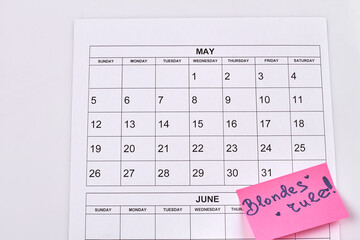 Blondes day concept. Calendar isolated on white background. Blond rules on pink sticker note.