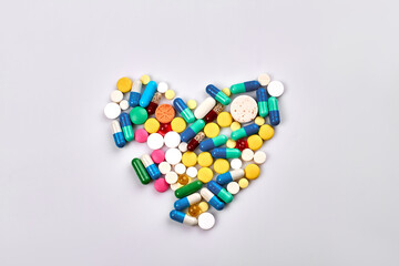 Heart of pills and capsules isolated on white background. Top view flat lay.