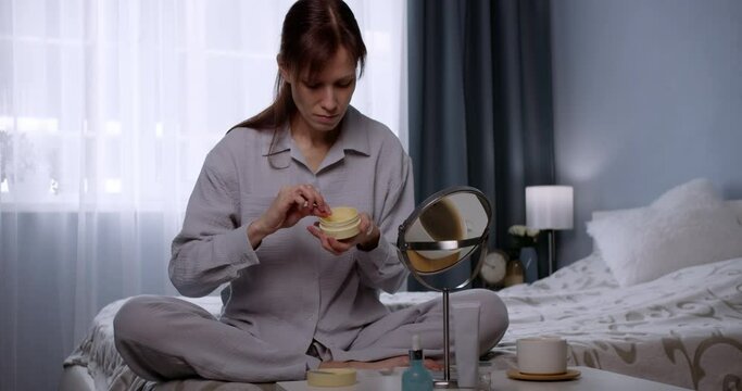 Young woman at home doing a skincare beauty routine applying under eye patch