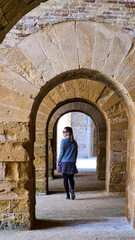 Fototapeta na wymiar Tourist woman walking through inside vaults of the Castello Maniace. Interior of ancient citadel fortress Maniace Castle on island of Ortygia in Syracuse, Sicily, Italy, Europe EU. UNESCO Site. Tunnel