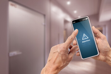 Man holding mobile phone with smart home remote system alarm interface