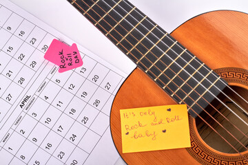 Rock n roll day concept. 13 april marked in calendar. Classic wooden guitar on white background.