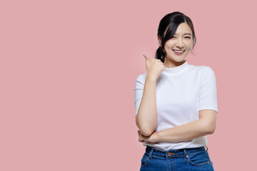 Happy young Asian woman feeling happiness and gesture thumb up on isolated pink background with copy space.