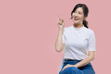 Happy young Asian woman feeling happiness and gesture pointing finger on isolated pink background...