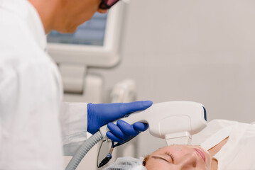 Woman receiving face skin phototherapy procedure in clinic of aesthetic cosmetology