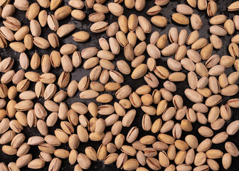 unpeeled pistachio on black background, top view