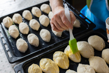 Woman brushing pies with beaten eggs before to put them in oven. Home baking.