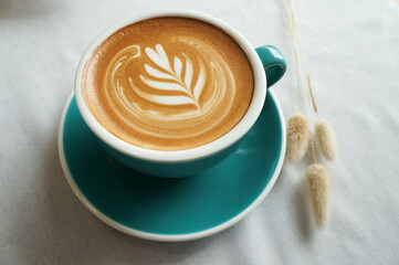 Top view of hot coffee latte in a green ceramic mug is placed on the table.