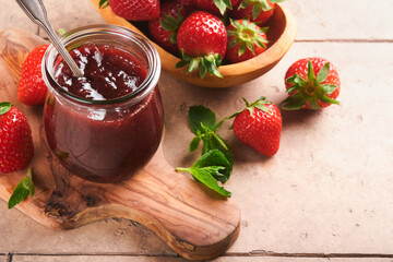 Strawberry jam. Strawberry jam in glass jar with fresh berries plate on an old cracked tile table background, closeup. Homemade strawberry fruity jam. Top view with copy space.