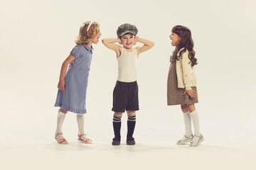Naklejka premium Portrait of three children playing together, girls screaming at boy isolated over grey studio background