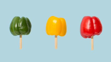 Three colorful sweet peppers on ice cream sticks. Minimal summer concept.