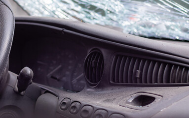 Close-up of the steering wheel of a car after an accident. The driver's airbags did not deploy. Soft focus. Broken windshield with steering wheel. Vehicle interior. Black dashboard and steering wheel.