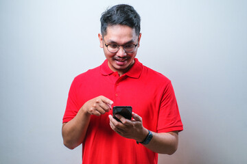 Photo of cheerful positive handsome man wearing casual shirt holding and pointing smartphone smiling searching information