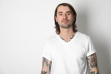 Young man with tattoos on arms against white background