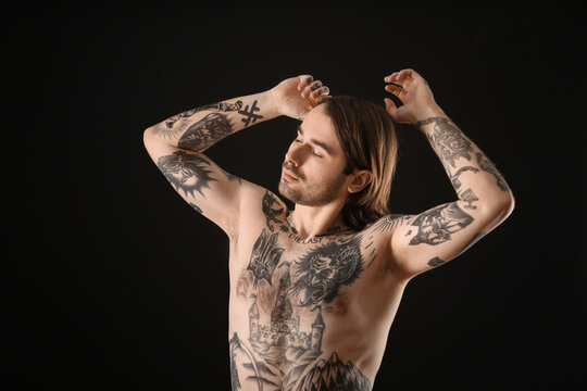 Young man with tattoos on body against black background