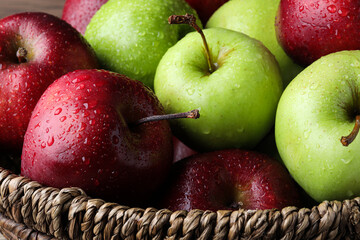Fresh ripe green and red apples with water drops in wicker bowl, closeup
