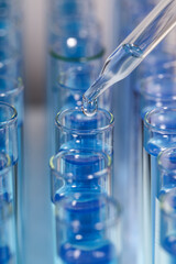 Dripping reagent into test tube with blue liquid on light background, closeup. Laboratory analysis