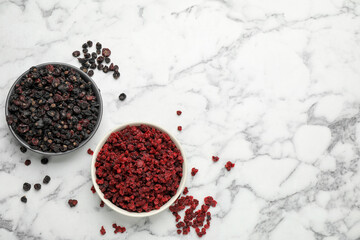Dried red and black currant berries on white marble table, flat lay. Space for text