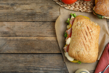 Delicious sandwich with vegetables, ham and mayonnaise served on wooden table, flat lay. Space for text
