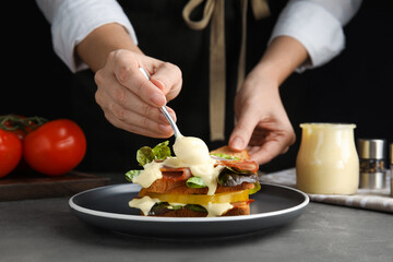 Woman making sandwich with mayonnaise at grey table, closeup - obrazy, fototapety, plakaty