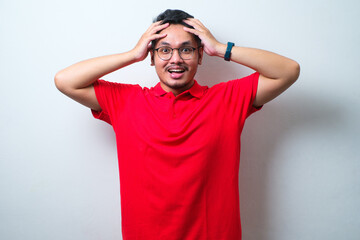 Fototapeta na wymiar Portrait of a confused young handsome man wearing casual shirt and glasses with hands on his head