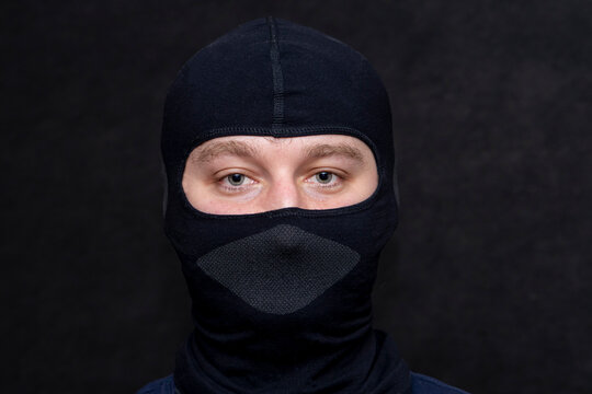 Portrait of a serious man in a balaclava. A black mask on his face, hides his appearance. Perhaps he is a criminal or a hacker, a military sniper.