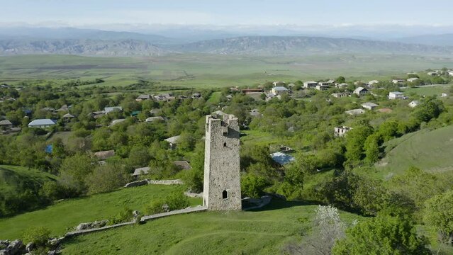 Watchtower Of Noste Castle On Lush Green Hill In Kaspi, Shida Kartli, Georgia. aerial drone orbit