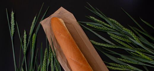 fresh bread on a black background with green wheat ears